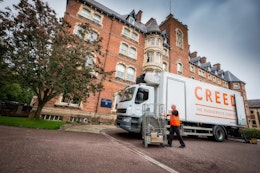Creed Lorry in front of red brick building with tree