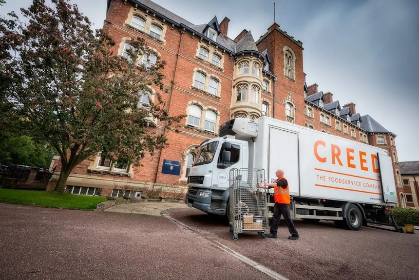 Creed Lorry in front of red brick building with tree