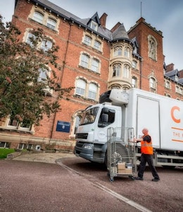 Creed Lorry in front of red brick building with tree