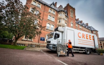 Creed Lorry in front of red brick building with tree