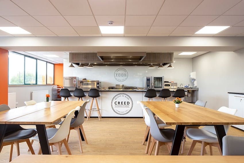 Large wooden dining tables in front of the creed innovation kitchen 