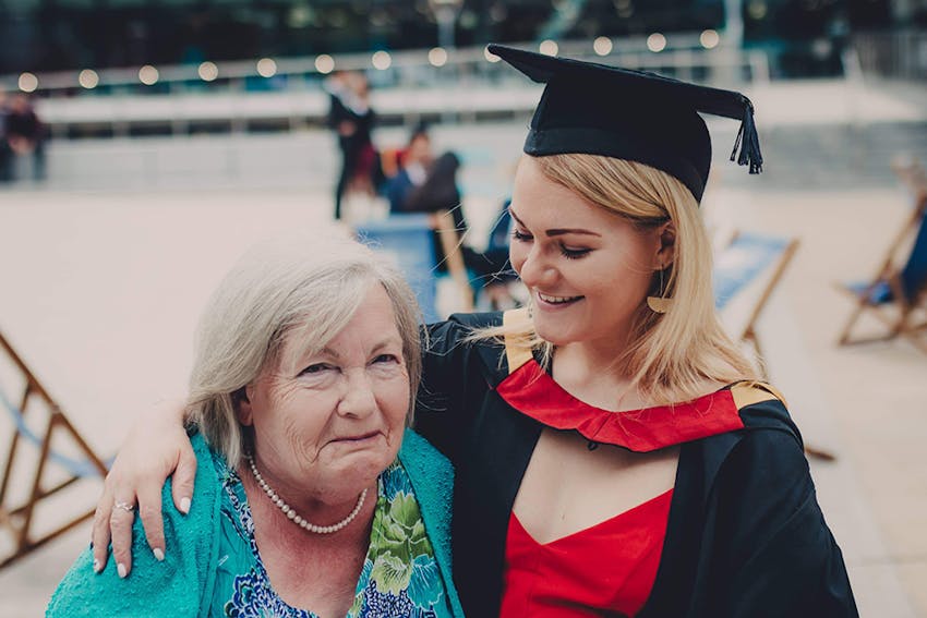 a young girl and her grandma embracing at graduation ceremony 
