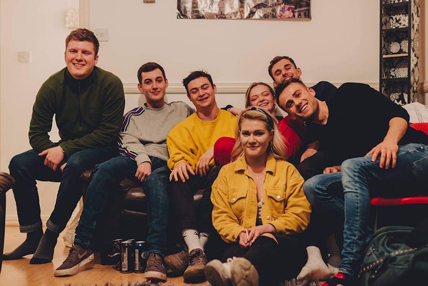 a group of young university students posing for photograph on a sofa 