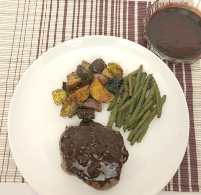 a white plate with steak covered in chocolate and coffee sauce, green beans and roasted vegetables 