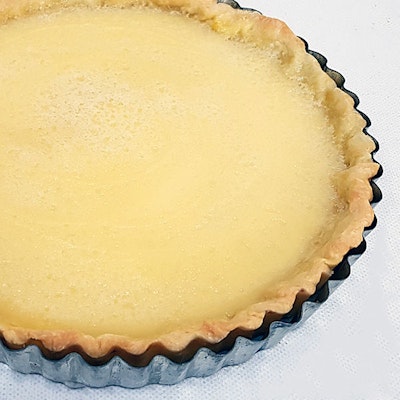 lemon tart dusted with sugar and in a grey latticed baking dish 
