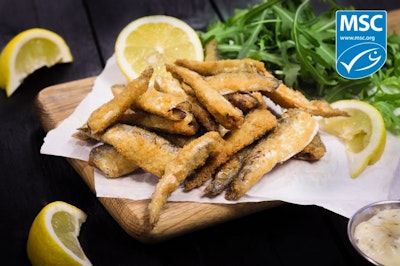 paramount msc coated whitebait fish on a wooden chopping board served with salad and sliced lemons 