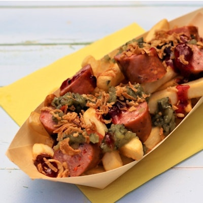 fries topped with wild boar frankfurter, crispy onions, bostongurkha, and lingonberry jam in a cardboard try 