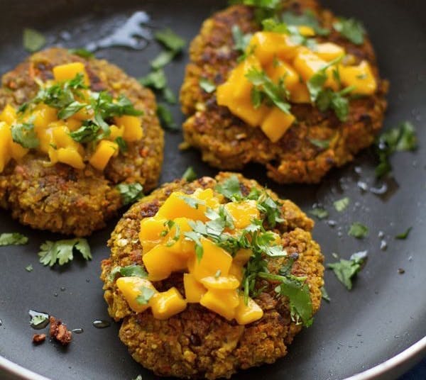 three crispy vegan burgers topped with fresh herbs and served on a plate 