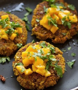 three crispy vegan burgers topped with fresh herbs and served on a plate 