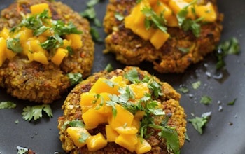 three crispy vegan burgers topped with fresh herbs and served on a plate 