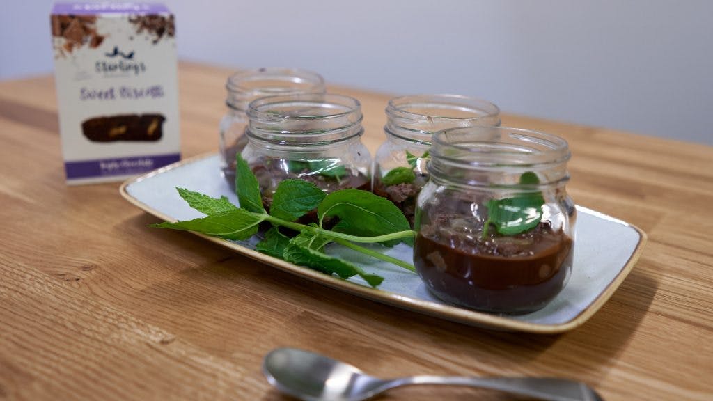 Deliciously Chocolatey Cheesecake a rectangle plate with four small cheesecakes in glass jars displayed with fresh mint