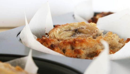 Eat Allergy Safe Banana Breakfast Muffins Golden brown banana muffin inside a muffin tray lined with baking paper