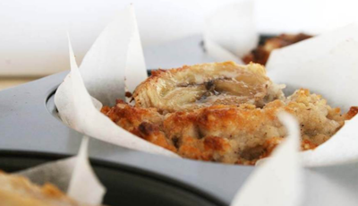 Golden brown banana muffin inside a muffin tray lined with baking paper 