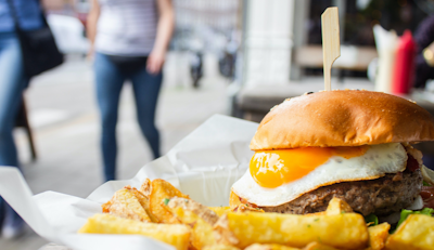 street food plate of crispy golden chips and a beef burger with a fried egg and a golden crisp bun 