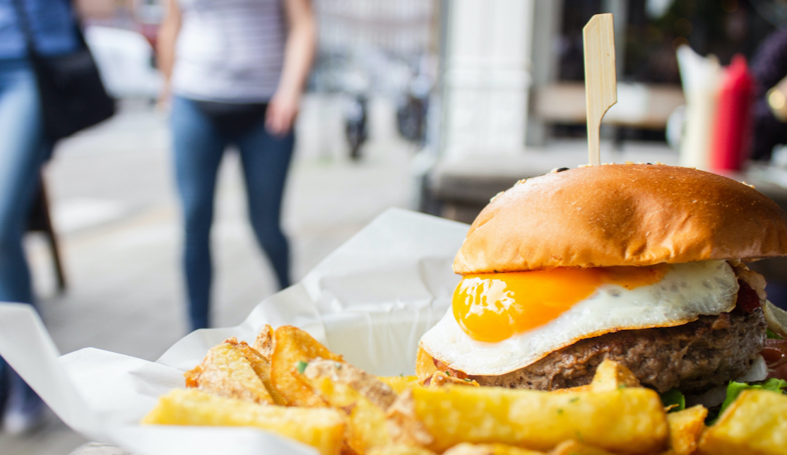 street food plate of crispy golden chips and a beef burger with a fried egg and a golden crisp bun 