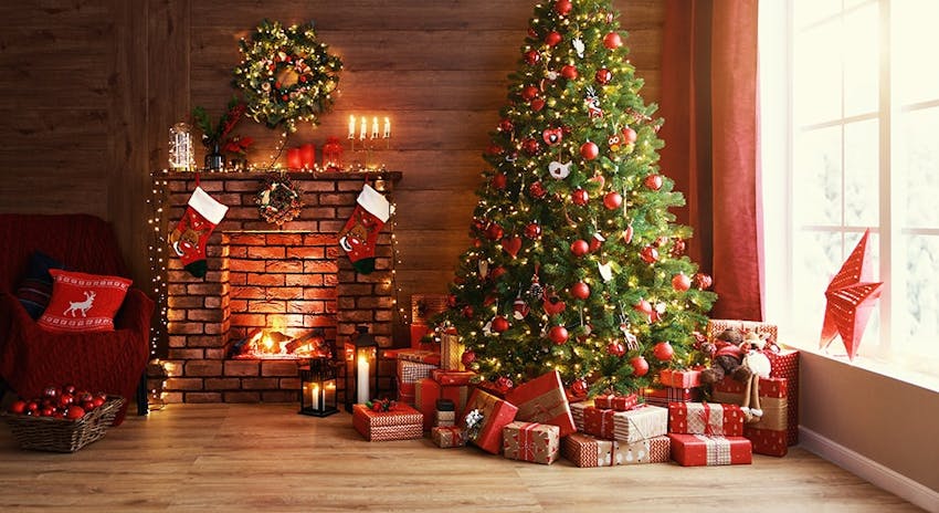 green christmas tree surrounded by wrapped presents next to a warming fireplace and a cosy armchair 