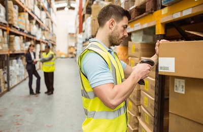 A man in a high vis searching the GTINs of products in a large warehouse