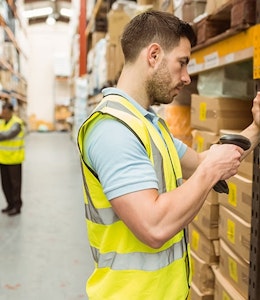 A man in a high vis searching the GTINs of products in a large warehouse