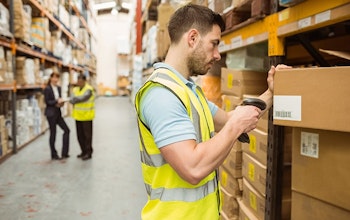 A man in a high vis searching the GTINs of products in a large warehouse
