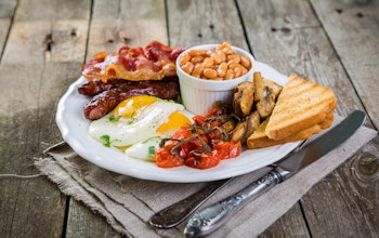 big english breakfast consisting of a pot of baked beans, brown bread, vine tomatoes, mushrooms, eggs, bacon and sausages 