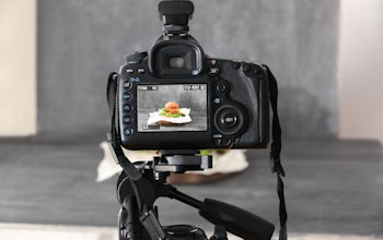a dslr camera on a tripod shooting a burger on a grey backdrop