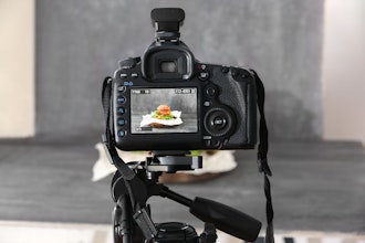 a dslr camera on a tripod shooting a burger on a grey backdrop