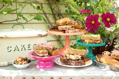 honeybuns gluten free cakes served on colourful tiered cake trays next to a cake tin on an outside garden table 