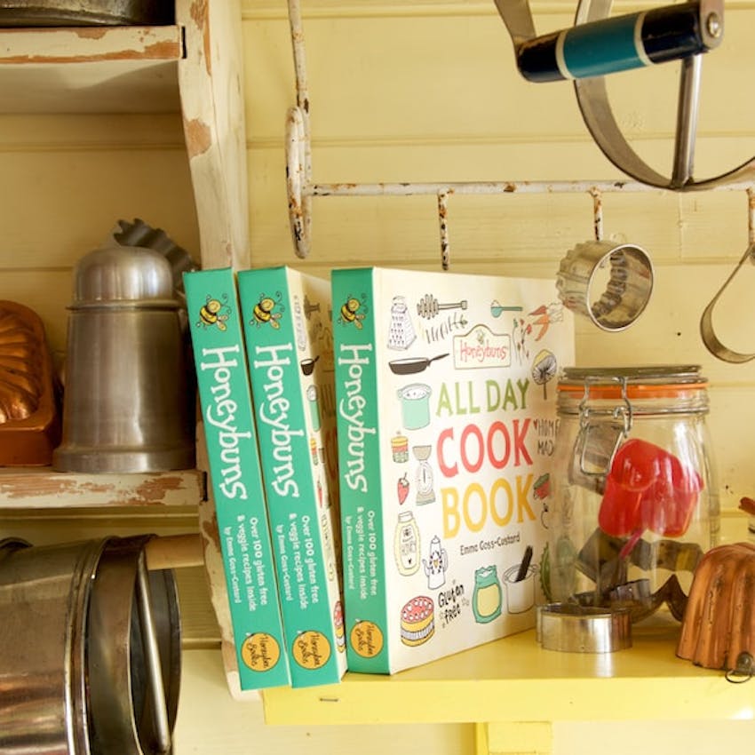 three honeybuns all day cookbook on yellow kitchen shelf surrounded by kitchen utensils and jars 