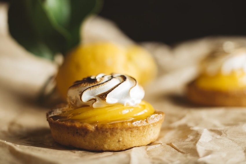 small lemon meringue tart with blow torched meringue and lemon curd on baking paper 
