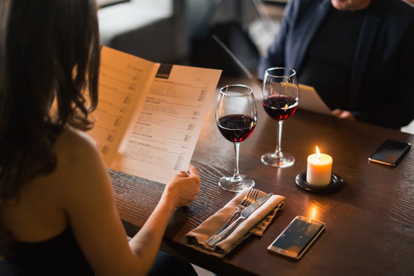 couple dining out and drinking red wine look at menu's before ordering food