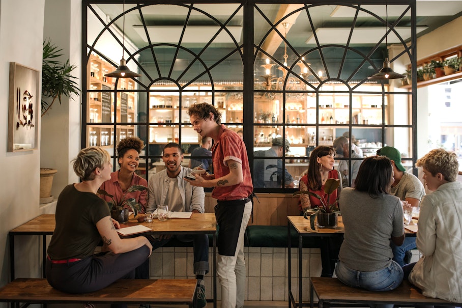 Make sure you discuss your allergy with staff when ordering food. girl eating out with friends discusses allergies with waiter as she orders food