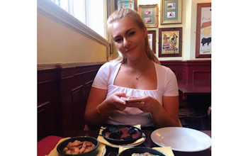 a young girl smiling at a restaurant dinner table behind three plates of tapas 