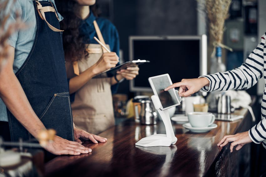 customer orders food in a restaurant on an ipad infront of waiting staff 