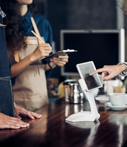 customer orders food in a restaurant on an ipad infront of waiting staff 