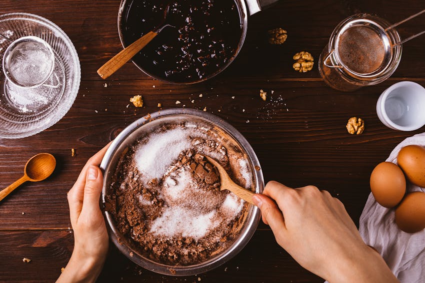 woman mixes gluten free flour into bowl to create cake mixture