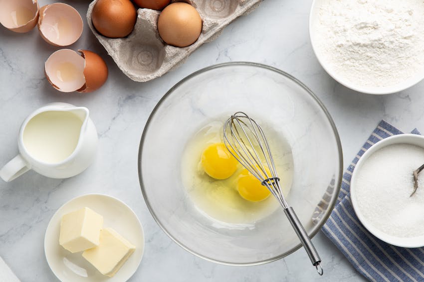 two eggs cracked into mixing bowl with whisk ready to add to the chocolate cake mixture 