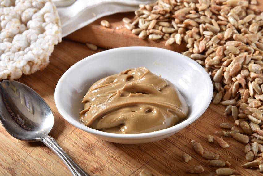 allergen friendly smooth sunflower seed butter in a white bowl next to a pile of sunflower seeds