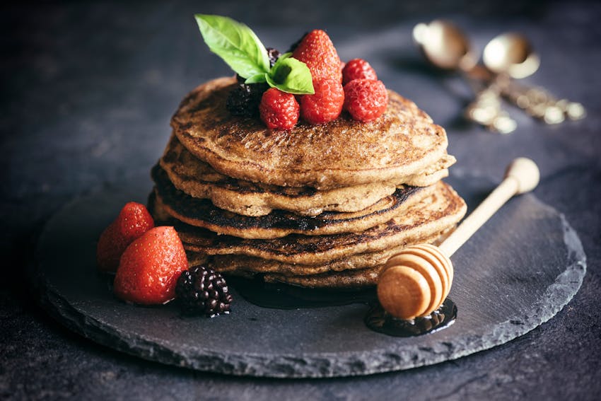 stack of fluffy gluten free pancakes with berries and honey 