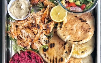 baking tray of harissa chicken pittas with baked carrots vegetables shredded chicken and beetroot dip 