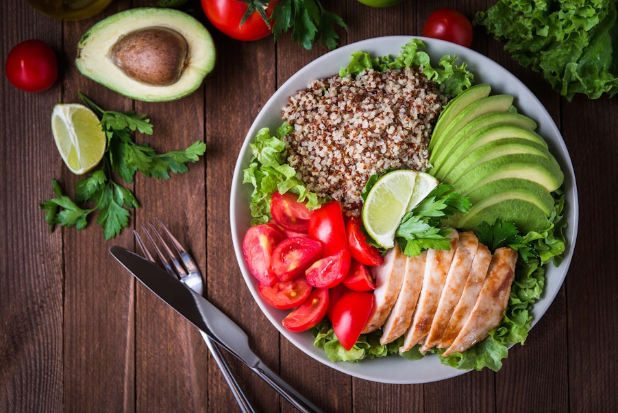 a healthy dish made up of avocado, salmon, whole grains, tomato and salad