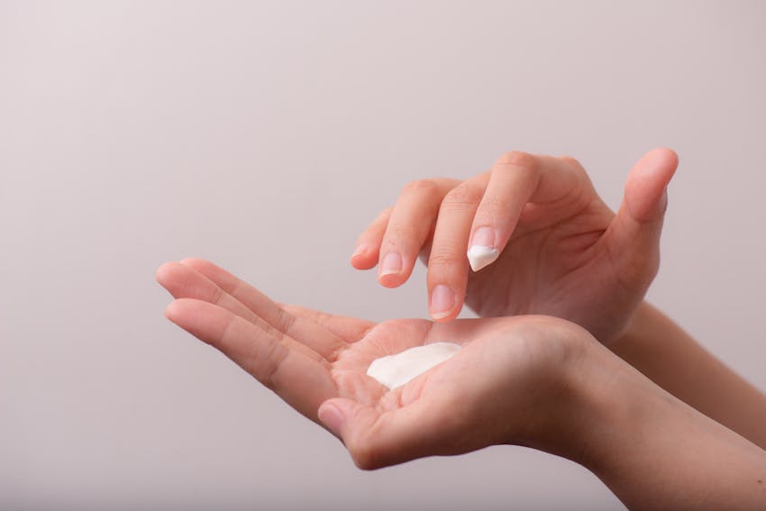 woman applying cream to hand to help soothe itchy skin from an allergic reaction 