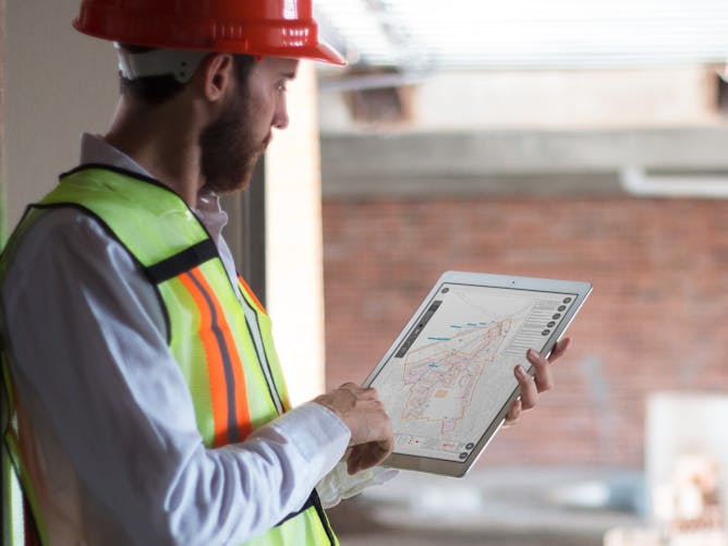 Man on building site using Heneghan Utilise app