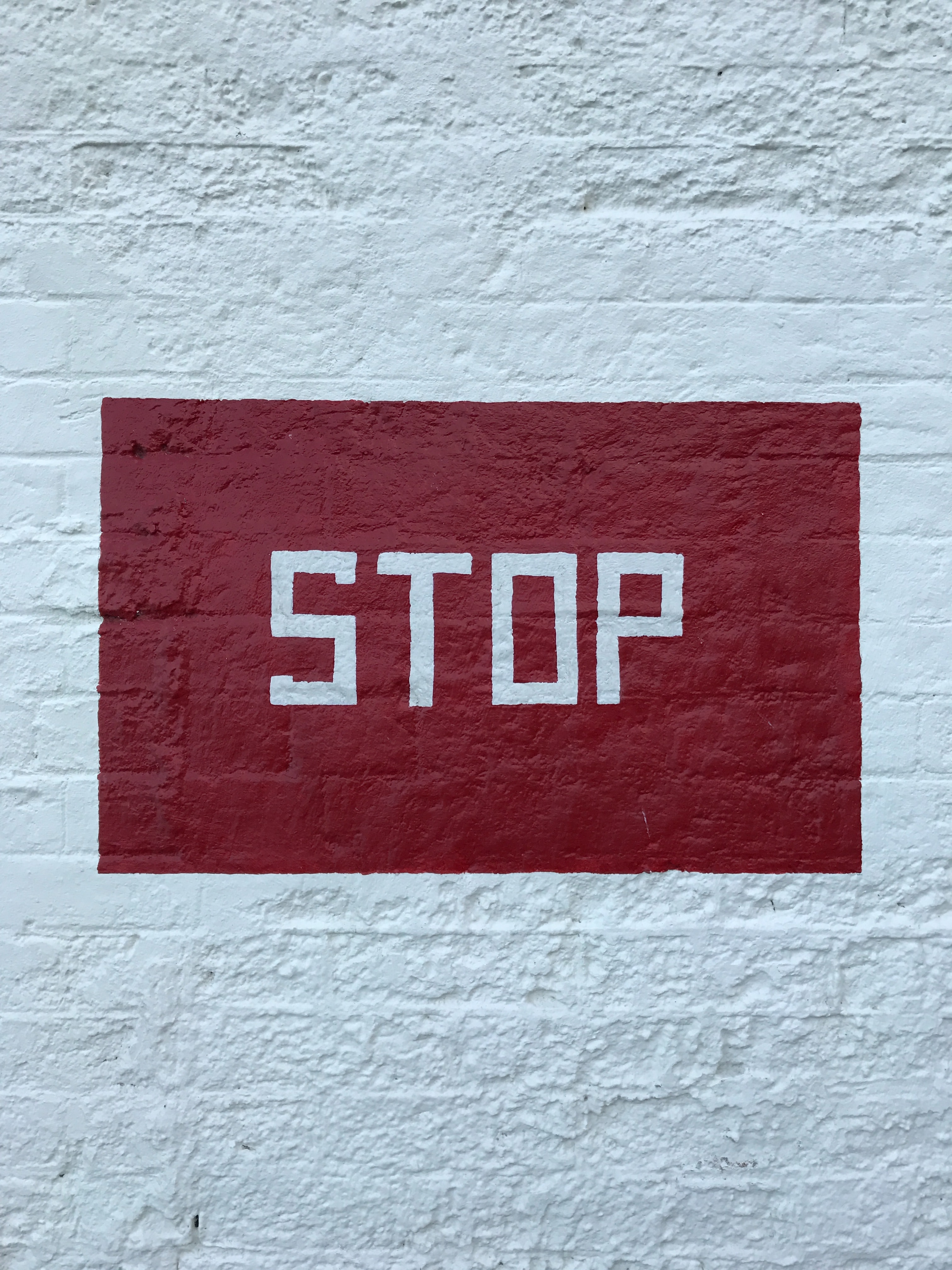 A red stop sign painted on a white wall