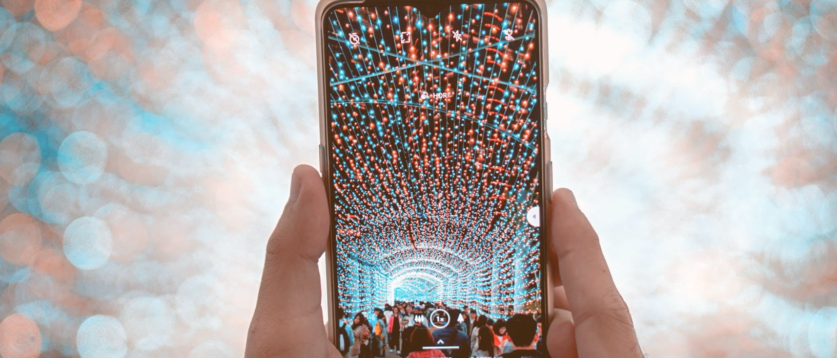 unknown person holding black smartphone capturing string lights