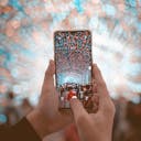 unknown person holding black smartphone capturing string lights