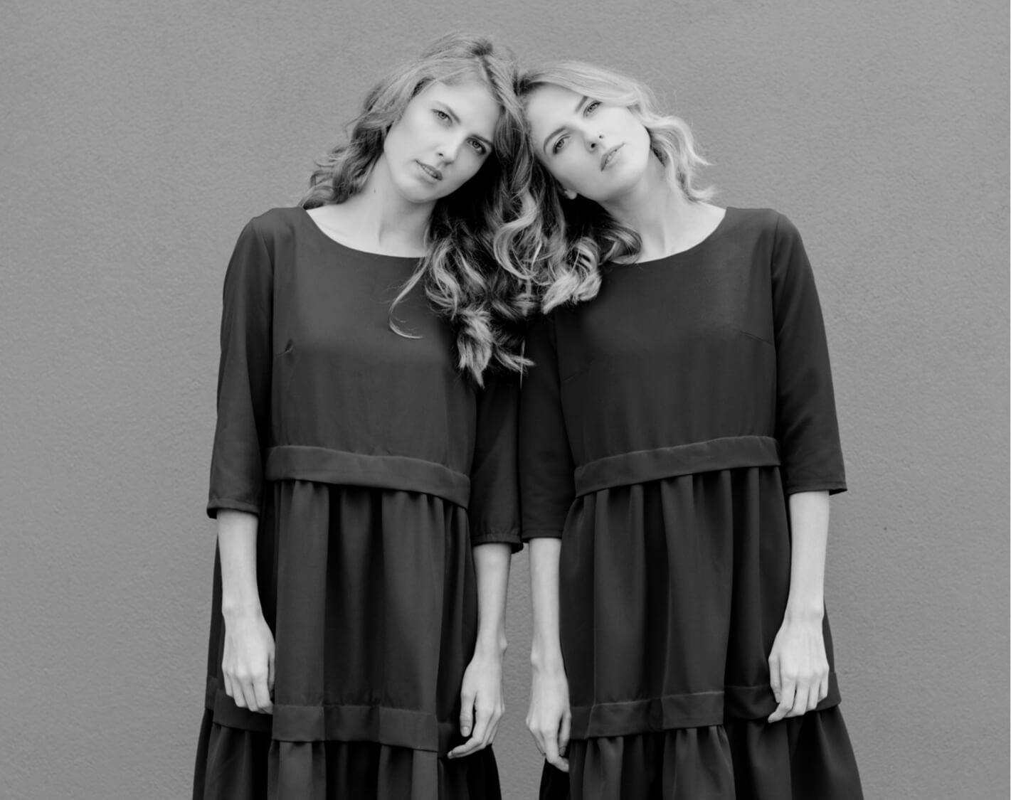 Beautiful blonde twins leaning on eachother.