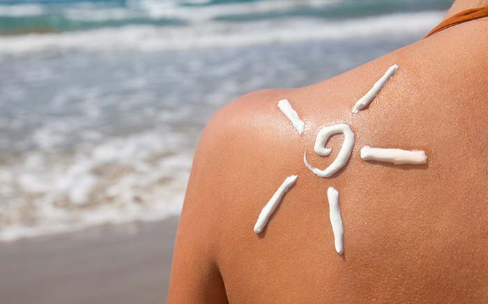 Woman with suntan lotion on her shoulder shaped like the sun 