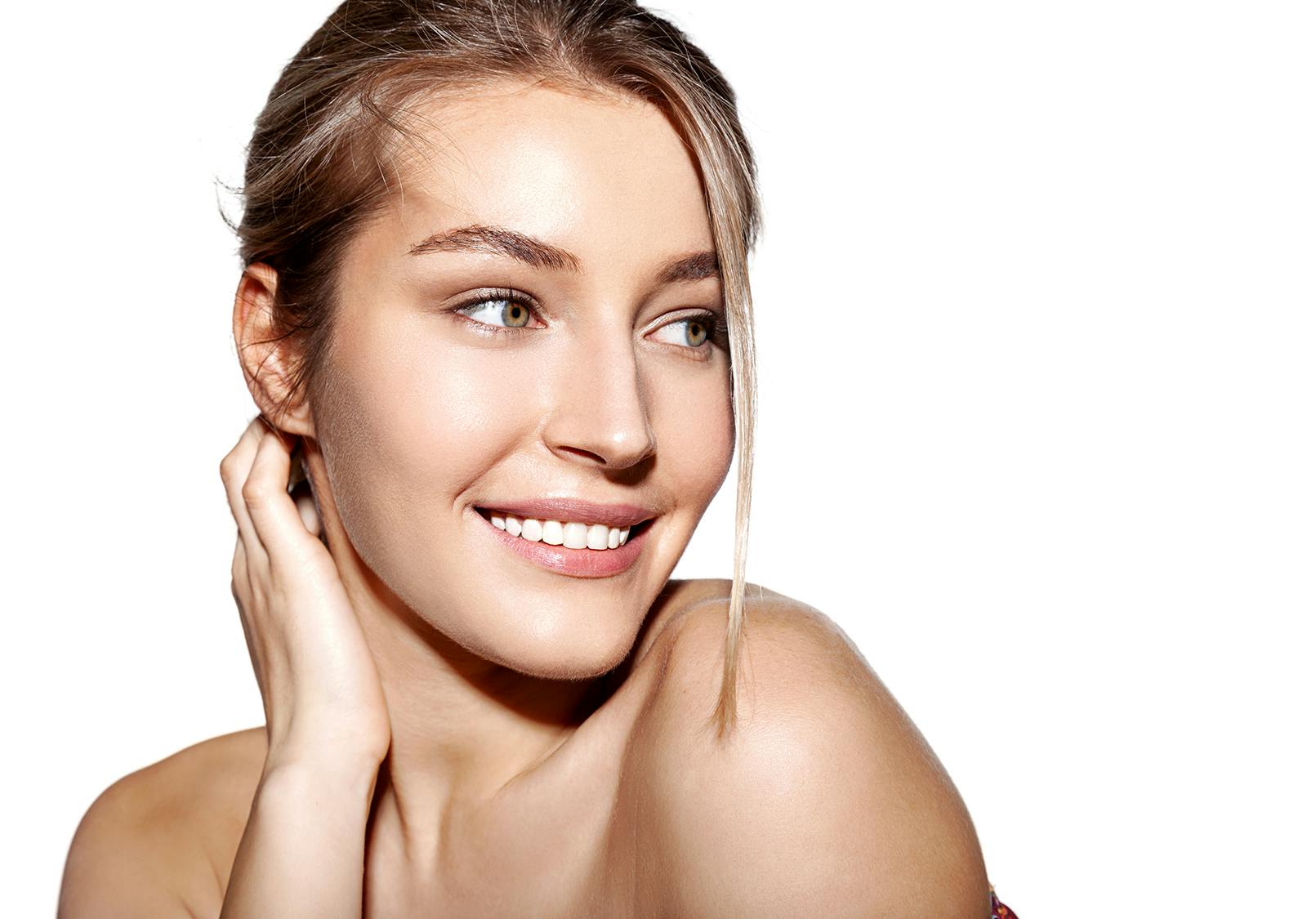 Beautiful young woman with smooth glowing skin smiling.