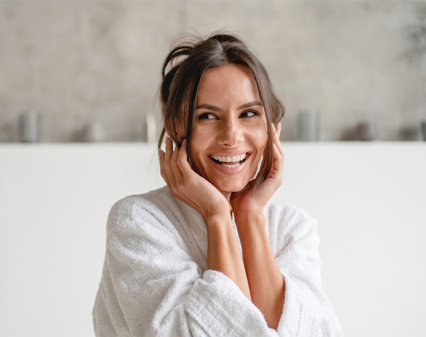 woman smiling, touching her face