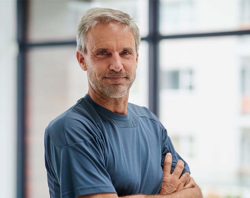 older man smiling, crossing his arms